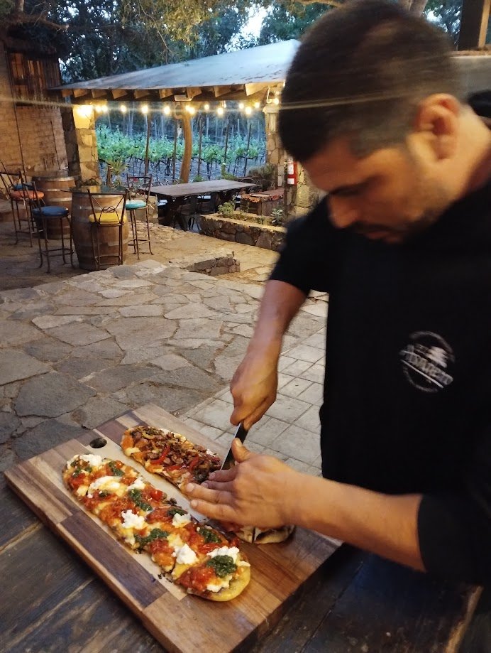 Cristian Palacios cortando flatbread artesanal entre viñedos